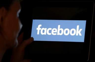 A woman looks at the Facebook logo on an iPad in this photo illustration