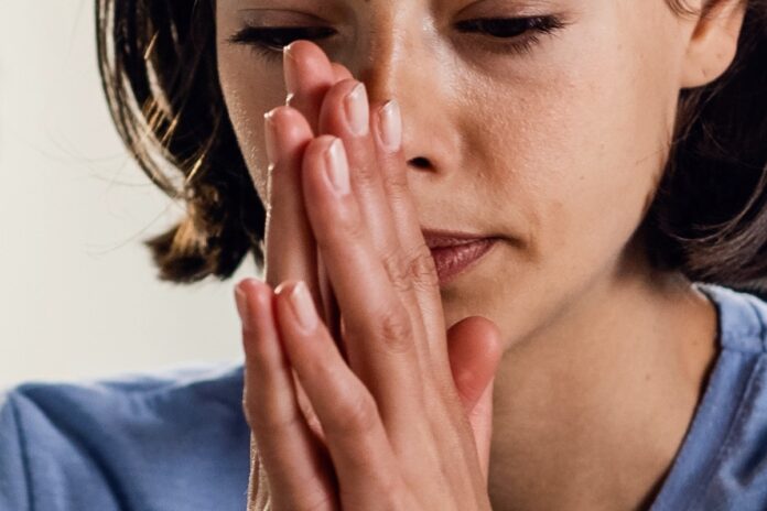 pensive-woman-with-hands-clasped-sitting-bed-thinking-something